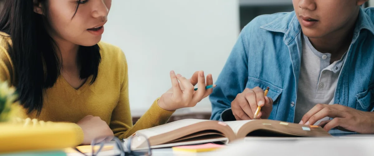 Female teacher teaching her and guiding her student in his assignment.
