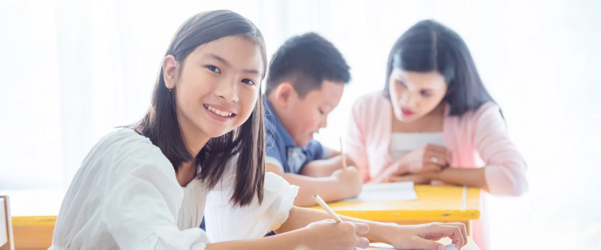 Young female student smiling and enjoying her time learning in the classroom.