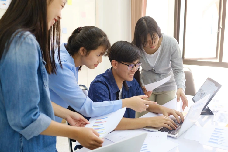 Group of tuition students gathering together to research and discuss on their assignment.