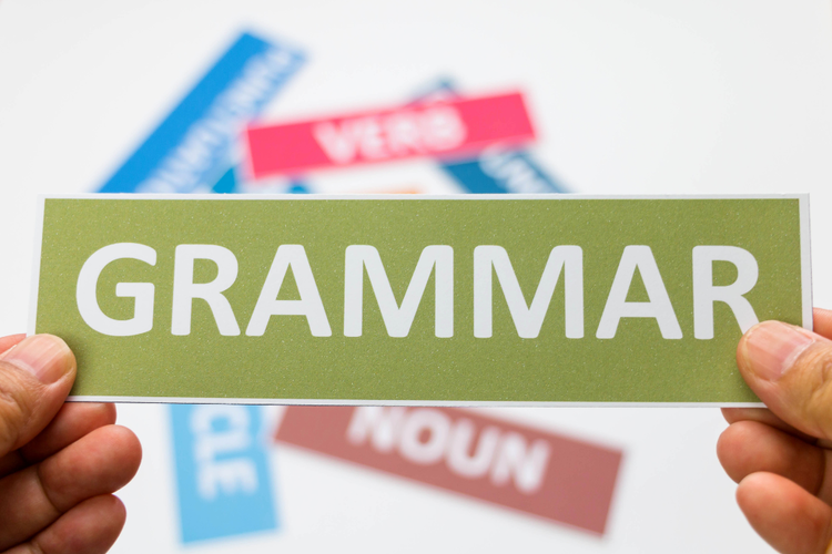 Hands holding card with the word grammar showing importance of grammar in vocabulary cloze exercises.