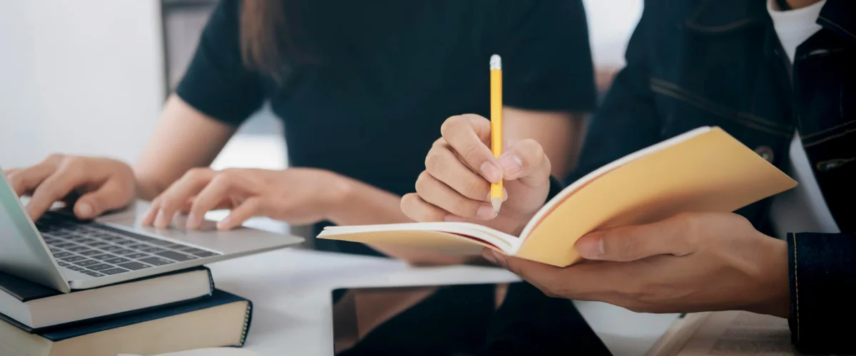 Student taking down important notes from laptop under a teacher's supervision.